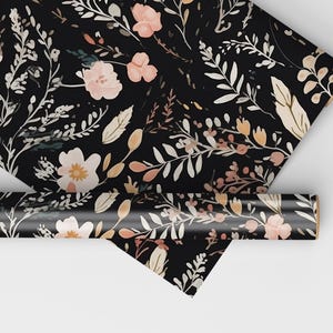 Op de afbeelding: Zwart inpakpapier met een bloemenpatroon met roze, witte en bruine bloemen en bladeren.
