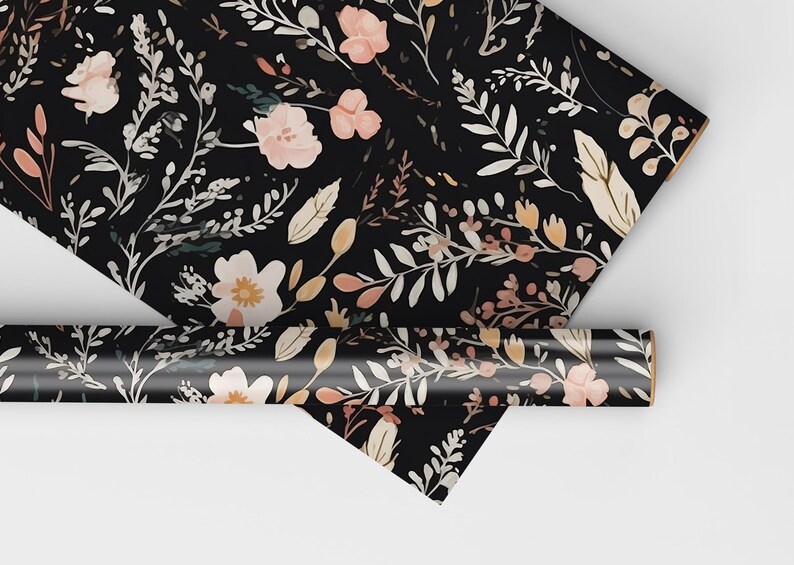 Op de afbeelding: Zwart inpakpapier met een bloemenpatroon met roze, witte en bruine bloemen en bladeren.
