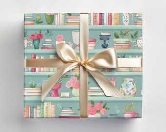 May include: A gift wrap design featuring a repeating pattern of bookshelves with books, flowers, and decorative items. The shelves are painted a light blue color and the background is a light green color. The design is tied with a gold ribbon.