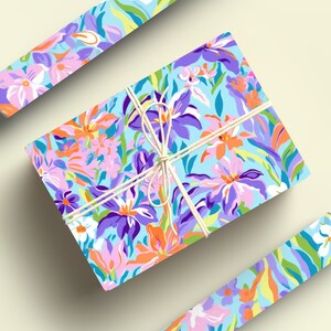 May include: A gift wrapped in blue floral wrapping paper with a white string bow. The wrapping paper features a colorful floral pattern with pink, purple, orange, and green flowers.