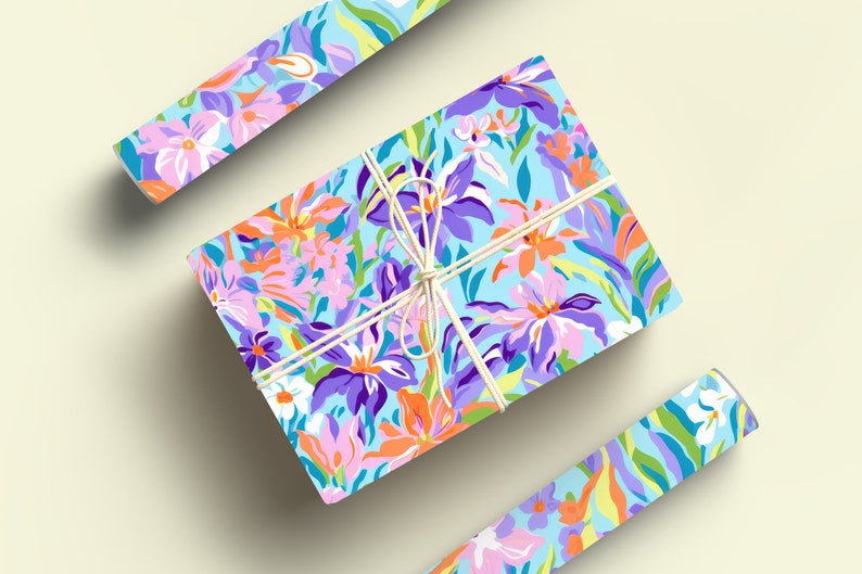 May include: A gift wrapped in blue floral wrapping paper with a white string bow. The wrapping paper features a colorful floral pattern with pink, purple, orange, and green flowers.