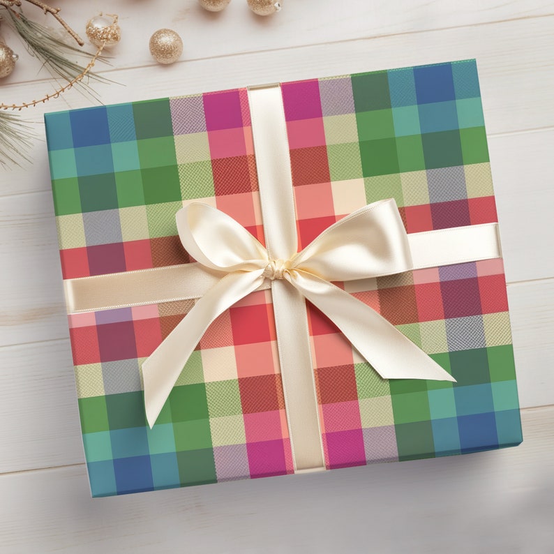 May include: A square gift box wrapped in colorful plaid paper with a cream-colored satin ribbon and bow. The plaid pattern features squares of blue, green, red, and pink. The box is on a white wooden surface.