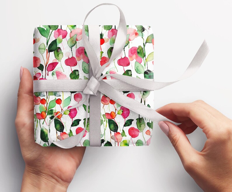 May include: A white gift box wrapped in floral patterned paper with pink, red, and green watercolor flowers. A silver ribbon is tied around the box.