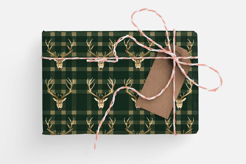 May include: A green and tan plaid gift wrap with a gold stag head pattern. The gift is tied with a white and pink twine and a brown gift tag.