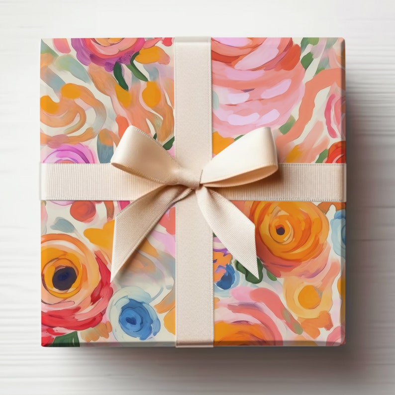 May include: A gift box wrapped in floral patterned paper with a cream-colored satin ribbon tied in a bow. The paper features a colorful abstract floral design with pink, orange, yellow, and blue hues.