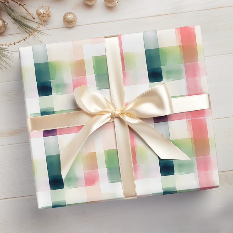 May include: A white gift box with a watercolor plaid pattern in shades of pink, green, and blue. The box is tied with a cream-colored satin ribbon with a bow.