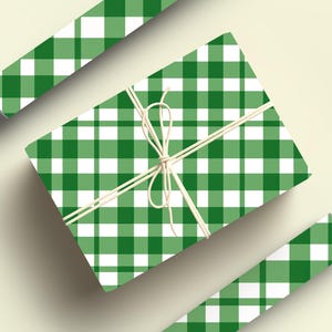 May include: Green and white gingham wrapping paper with a white ribbon tied around it. The paper is folded in half and the ribbon is tied in a bow.