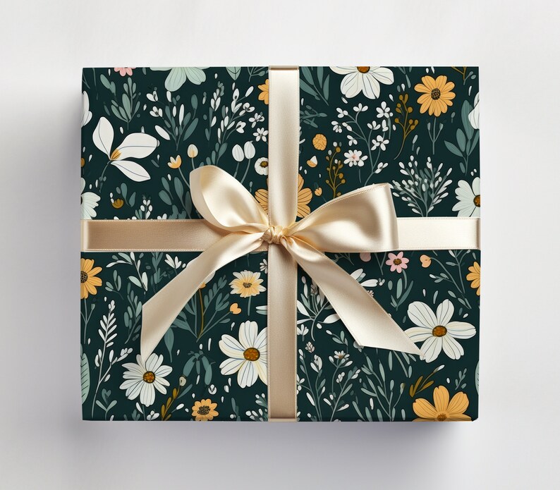 May include: A gift box wrapped in dark green wrapping paper with a floral pattern. The paper features white, yellow, and pink flowers with green leaves. A gold ribbon is tied around the box.