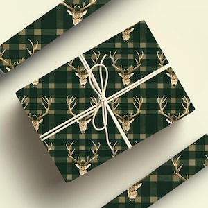 May include: Green and beige plaid wrapping paper with a gold stag head pattern. The paper is wrapped around a gift box and tied with twine.