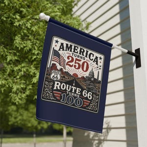以下が含まれることがあります： 「AMERICA TURNS 250」と「ROUTE 66 TURNS 100」の文字が入った濃紺の旗。アメリカ国旗、ルート66、象徴的なランドマークのイラストが描かれています。旗は屋外に吊るされています。