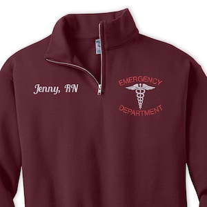 Pu&ograve; includere: Felpa bordeaux con zip a un quarto con il testo "Emergency Department" e un simbolo di caduceo ricamato in bianco. Il testo "Jenny, RN" &egrave; ricamato in bianco sul lato sinistro della felpa.