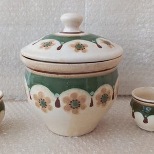 Könnte beinhalten: Ein Set aus drei Keramikbehältern mit einem grünen, braunen und weißen Blumendesign. Der größte Behälter hat einen Deckel.