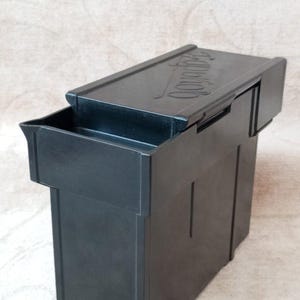 Może przedstawiać: Czarne plastikowe pudełko do przechowywania z klapką. Na klapce widnieje napis "Snap-on".