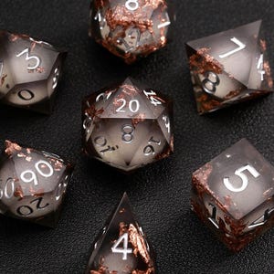 May include: A set of seven polyhedral dice for role-playing games. The dice are translucent grey with copper-coloured inclusions and white numbering. Includes a D4, D6, D8, D10, D12, D20, and a percentile die.
