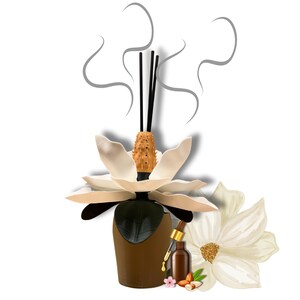 May include: A white ceramic flower diffuser with black reeds and a brown bottle of essential oil. The diffuser is shaped like a magnolia flower and has a decorative cork top. The bottle of essential oil has a dropper and is sitting on a white surface with almonds, a pink flower, and green leaves.