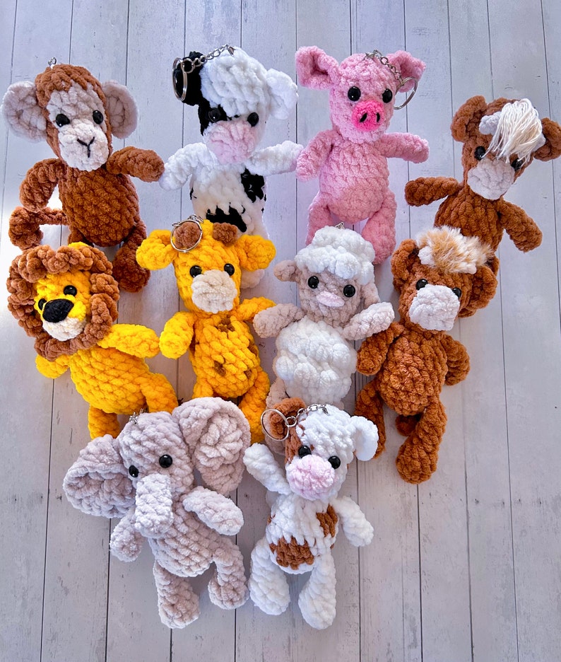 May include: A collection of ten crocheted animal keychains. The keychains are made of soft, colourful yarn and feature a variety of animals, including a lion, a monkey, a cow, a pig, a horse, a giraffe, an elephant, and a sheep.