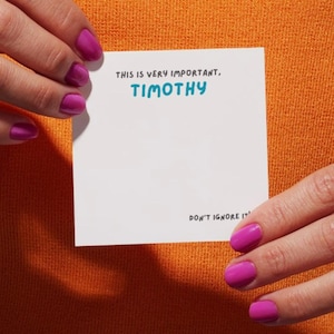 May include: White card with the text "This is very important, TIMOTHY. Don't ignore it." written in black marker.