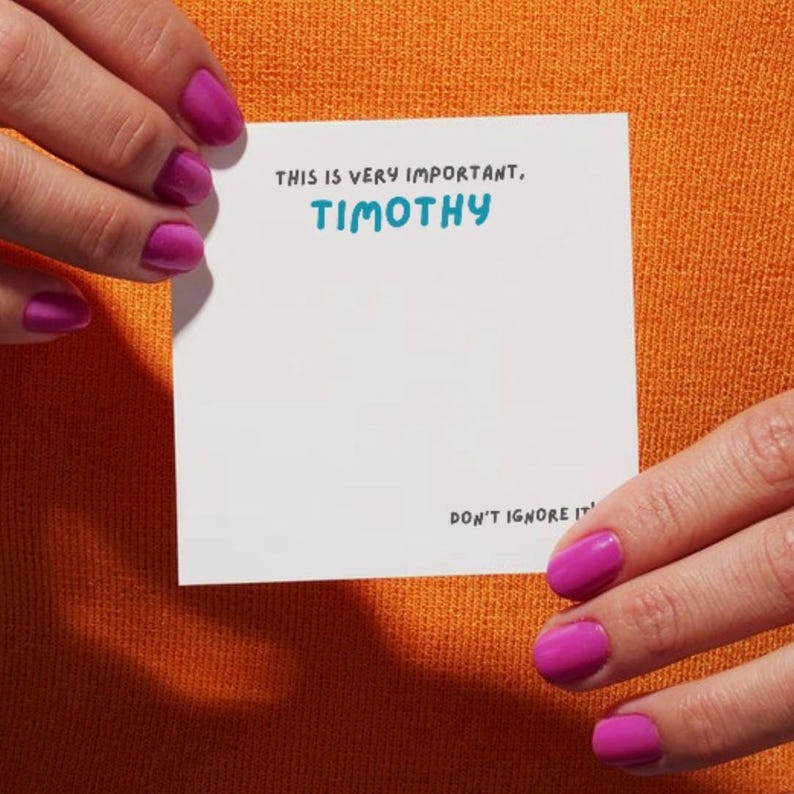 Op de afbeelding: Witte kaart met de tekst "Dit is erg belangrijk, TIMOTHY. Negeer het niet." geschreven met een zwarte stift.