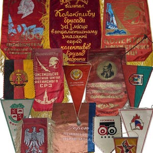 Może przedstawiać: Kolekcja zabytkowych proporców i transparentów, głównie czerwonych, ze złotymi frędzlami. Transparenty zawierają tekst cyrylicą i różne emblematy. Niektóre przedstawiają portrety.