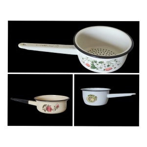 May include: Three enamelware kitchen strainers with black rims and floral designs. The strainers have handles and are white with green and red floral patterns.