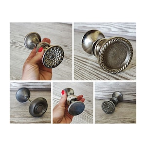 May include: Set of five antique door knobs with a silver finish. The knobs have various designs, including a round knob with a textured surface, a knob with a raised circular design, and a knob with a rope-like border.