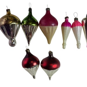 May include: A collection of nine vintage glass Christmas ornaments in various shapes and colors, including metallic gold, green, red, silver, and pink. Each ornament features a metal cap with a wire loop for hanging on a tree.