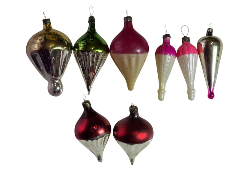 May include: A collection of nine vintage glass Christmas ornaments in various shapes and colors, including metallic gold, green, red, silver, and pink. Each ornament features a metal cap with a wire loop for hanging on a tree.