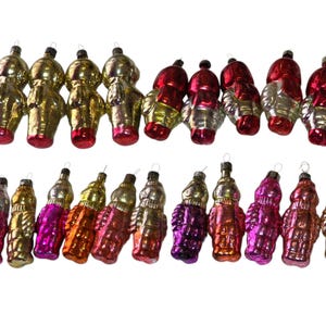 May include: A collection of vintage Christmas ornaments in various colors, including gold, silver, red, orange, and purple. The ornaments have a unique, retro design and are arranged in two rows against a white background.