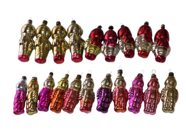 May include: A collection of vintage Christmas ornaments in various colors, including gold, silver, red, orange, and purple. The ornaments have a unique, retro design and are arranged in two rows against a white background.