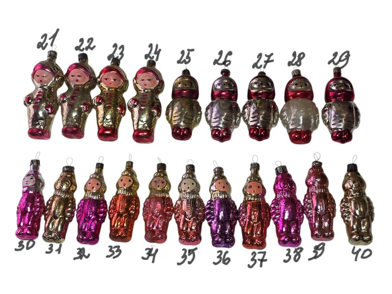 May include: A collection of twenty vintage glass ornaments shaped like figures in space suits, numbered 21 through 40. Each ornament features a painted face and metallic finish in various colors including gold, silver, pink, and red.