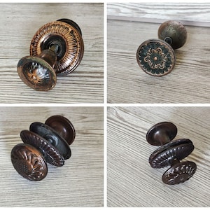 May include: Four antique door knobs with intricate designs. The knobs are made of metal and have a dark brown finish. Some of the knobs have a floral pattern.