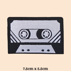 May include: Black and white embroidered iron-on patch of a cassette tape. The patch is 7.5cm by 5.5cm.