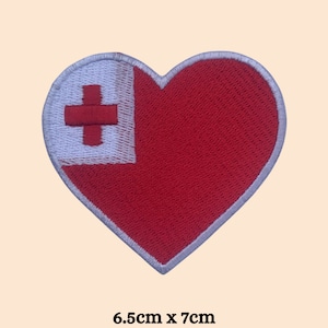 May include: Heart-shaped embroidered patch featuring the flag of Tonga. The patch is red with a white canton bearing a red cross. The patch measures 6.5cm x 7cm, or approximately 2.5 inches x 2.75 inches.