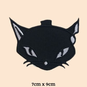 Könnte beinhalten: Schwarzer gestickter Bügel-Patch mit einem Katzenkopf mit weißen Augen und Schnurrhaaren. Der Patch misst 7 cm x 9 cm.