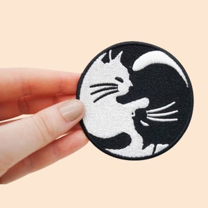 Peut inclure: Patch brodé noir et blanc de deux chats dans un design yin yang.