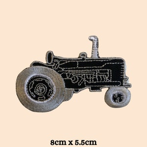 May include: Black and white embroidered iron-on patch of a tractor. The patch is 8 inches by 5.5 inches.