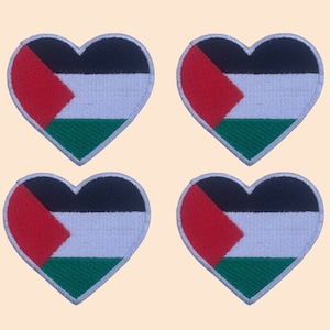 Puede incluir: Cuatro parches en forma de corazón con los colores de la bandera palestina: rojo, blanco, negro y verde. Los parches están bordados con los colores de la bandera.