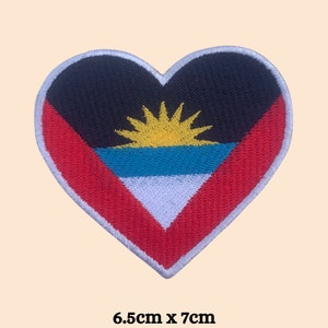 May include: A heart-shaped embroidered patch featuring the flag of Antigua and Barbuda. The flag is red, white, blue, and yellow with a sun in the center. The patch is 6.5 inches by 7 inches.