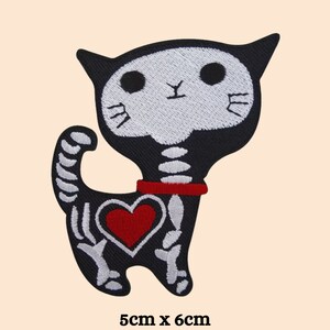 May include: Black and white embroidered iron-on patch of a skeleton cat with a red heart. The cat is wearing a red collar. The patch is 5 cm by 6 cm.