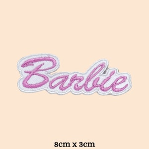 May include: Embroidered patch with the word "Barbie" in a cursive font, outlined in white with pink stitching. The patch measures 8cm x 3cm. The patch is on a light peach background.