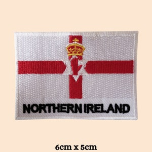 Peut inclure: Écusson brodé blanc représentant le drapeau de l'Irlande du Nord. Le drapeau présente une croix rouge sur fond blanc avec une main rouge et une couronne dorée au centre. Le texte "NORTHERN IRELAND" est brodé en noir sous le drapeau. L'écusson mesure 6 cm sur 5 cm.