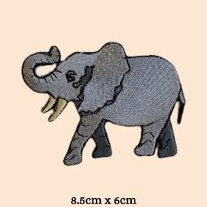 Könnte beinhalten: Ein grauer gestickter Bügelaufkleber mit einem Elefanten, der seinen Rüssel in die Luft reckt. Der Aufkleber ist 8,5 cm x 6 cm groß.