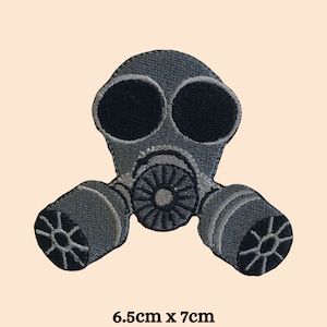 Op de afbeelding: Een grijze geborduurde patch van een gasmasker met zwarte details. De patch is 6,5 cm bij 7 cm.