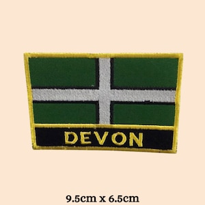 May include: A green and white embroidered patch with a yellow border and the word "DEVON" in black lettering. The patch is 9.5 inches by 6.5 inches.
