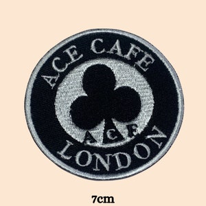 May include: Black and white embroidered patch with the text "Ace Cafe London" and a stylised clover design. The patch is 7 cm in diameter.