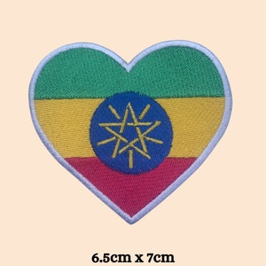 May include: A heart-shaped embroidered patch with the flag of Ethiopia. The flag features green, yellow, and red stripes with a blue star in the center. The patch measures 6.5 inches by 7 inches.
