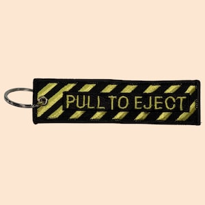 May include: Black and yellow striped key chain with the text "PULL TO EJECT" in yellow.