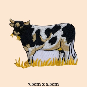 May include: Embroidered patch featuring a black and white cow with tan accents, standing in yellow grass. The patch measures 7.5cm x 5.5cm (approximately 3 x 2.2 inches).