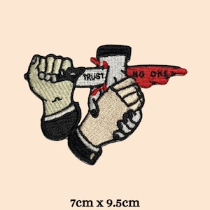 May include: Embroidered iron-on patch featuring two hands shaking, one hand holding a knife with the word "TRUST" on the blade, the other hand holding a red banner with the words "NO ONE". The patch is 7cm x 9.5cm.
