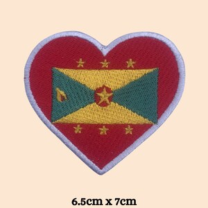 May include: A red heart-shaped patch with a white outline, featuring the flag of Grenada. The flag is yellow, green, and red with a star and a nutmeg. The patch is 6.5 inches by 7 inches.
